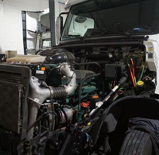 A Volvo tractor with the hood tipped forward and the engine open for service